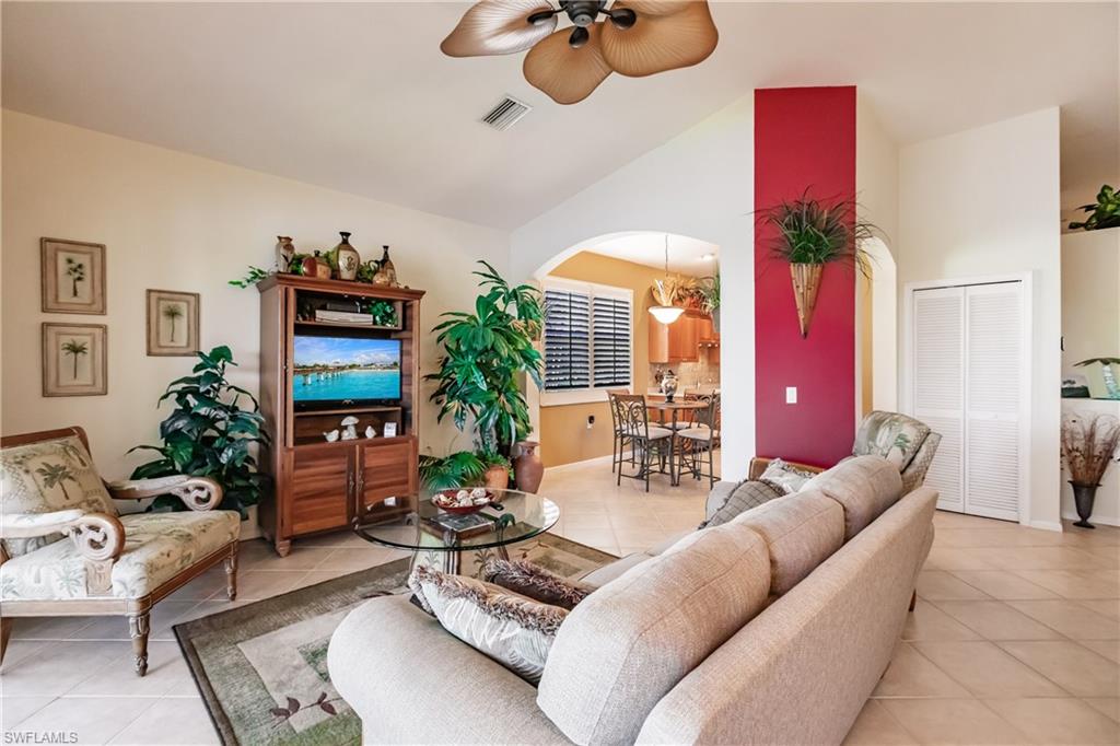 Living area featuring light tile patterned floors, ceiling fan, high vaulted ceiling, and arched walkways