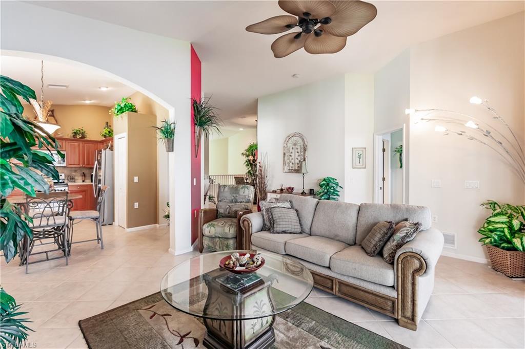 Living area featuring light tile patterned floors, arched walkways, and a ceiling fan