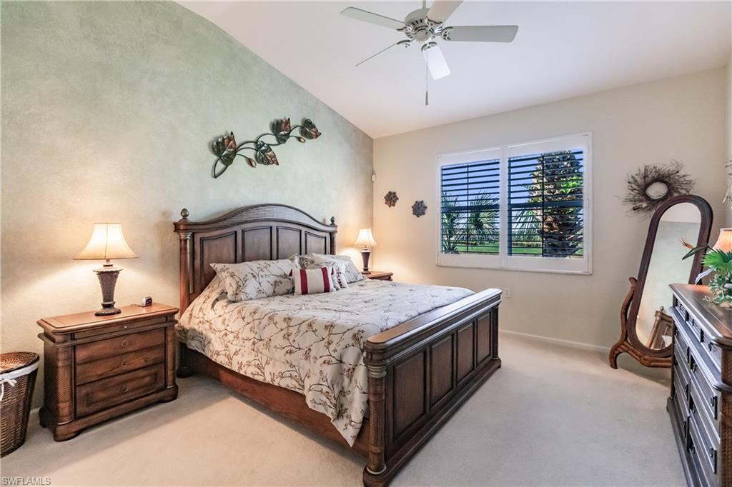 Bedroom with ceiling fan, light colored carpet, and vaulted ceiling