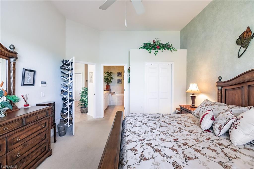 Bedroom with light colored carpet, a closet, ceiling fan, and a towering ceiling
