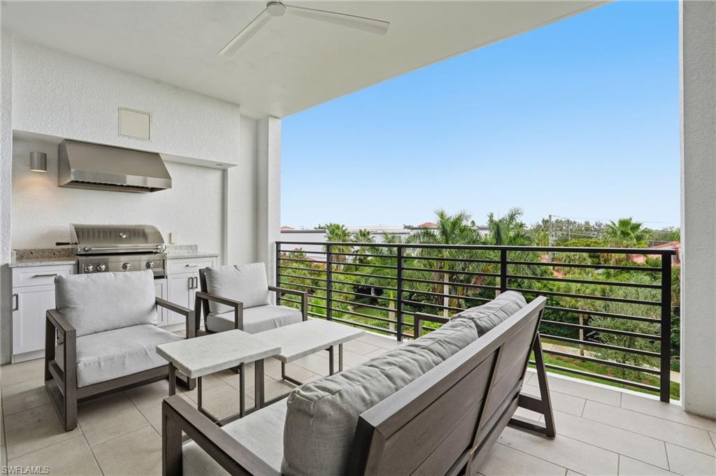 Balcony with an outdoor hangout area, ceiling fan, and exterior kitchen