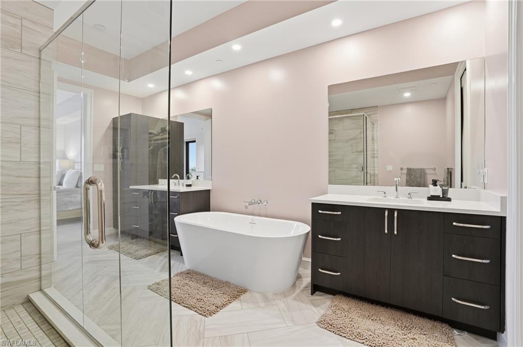 Full bathroom with two vanities, a freestanding bath, recessed lighting, a shower stall, and ensuite bathroom