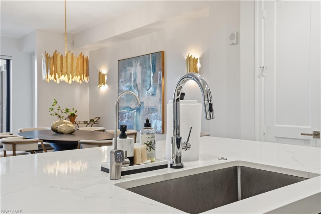 Kitchen view of light stone countertops and hanging light fixtures