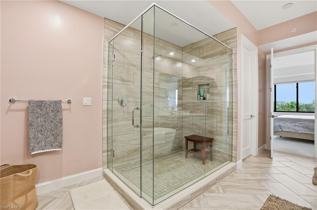 Ensuite bathroom featuring a shower stall and baseboards