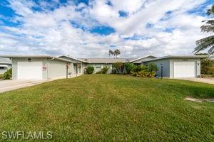 Ranch-style home featuring an attached garage, driveway, and a front lawn