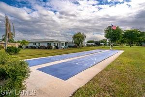 View of community featuring shuffleboard, a lawn, and driveway