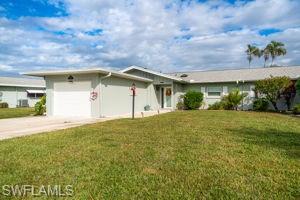 Ranch-style home featuring a garage, concrete driveway, and a front lawn