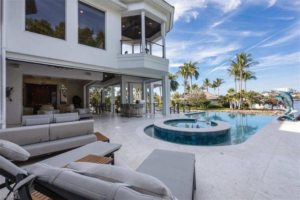 View of swimming pool featuring a balcony, a sunroom, a pool with connected hot tub, an outdoor living space, and a patio