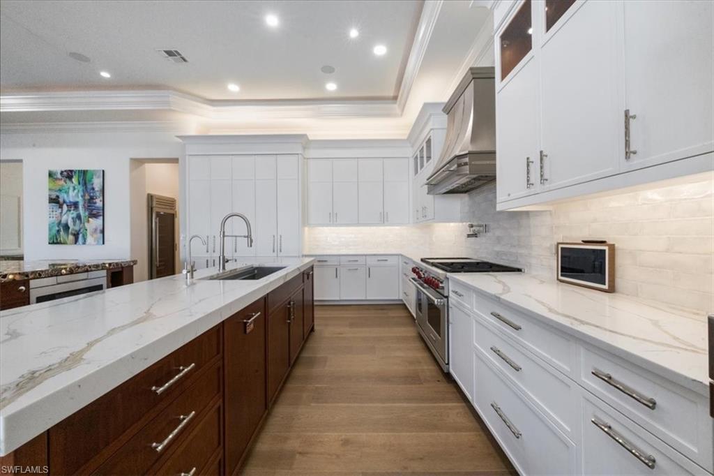 Kitchen with glass insert cabinets, light stone countertops, ornamental molding, double oven range, and white cabinets