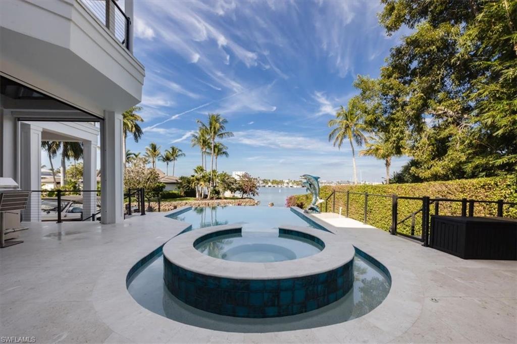View of swimming pool featuring a patio area, a pool with connected hot tub, and a water view