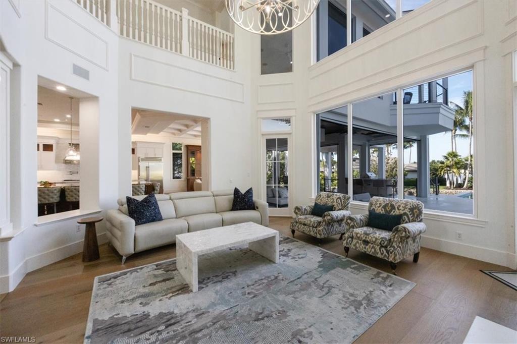 Living area featuring a high ceiling, a chandelier, and wood finished floors