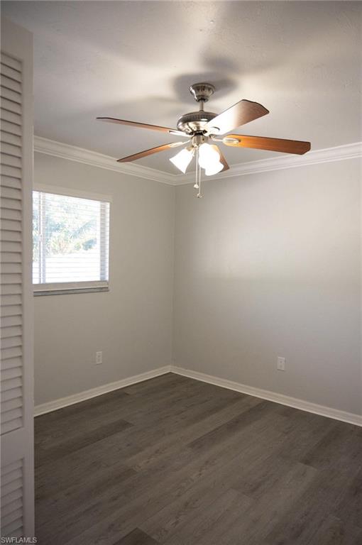 Unfurnished room with ornamental molding, dark wood-type flooring, and ceiling fan