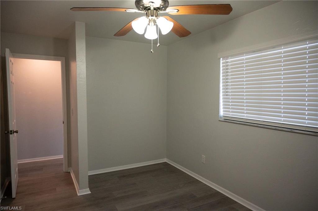 Empty room featuring ceiling fan and dark wood-style flooring