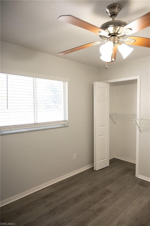 Unfurnished bedroom with a closet, dark wood-style flooring, and ceiling fan