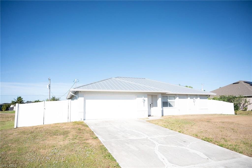 Single story home with a metal roof, concrete driveway, and a garage