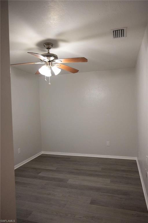 Unfurnished room featuring dark wood-type flooring and ceiling fan
