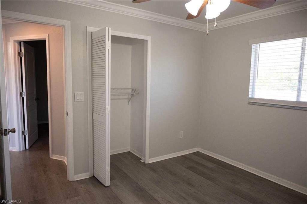 Unfurnished bedroom featuring crown molding, a closet, dark wood-style floors, and a ceiling fan