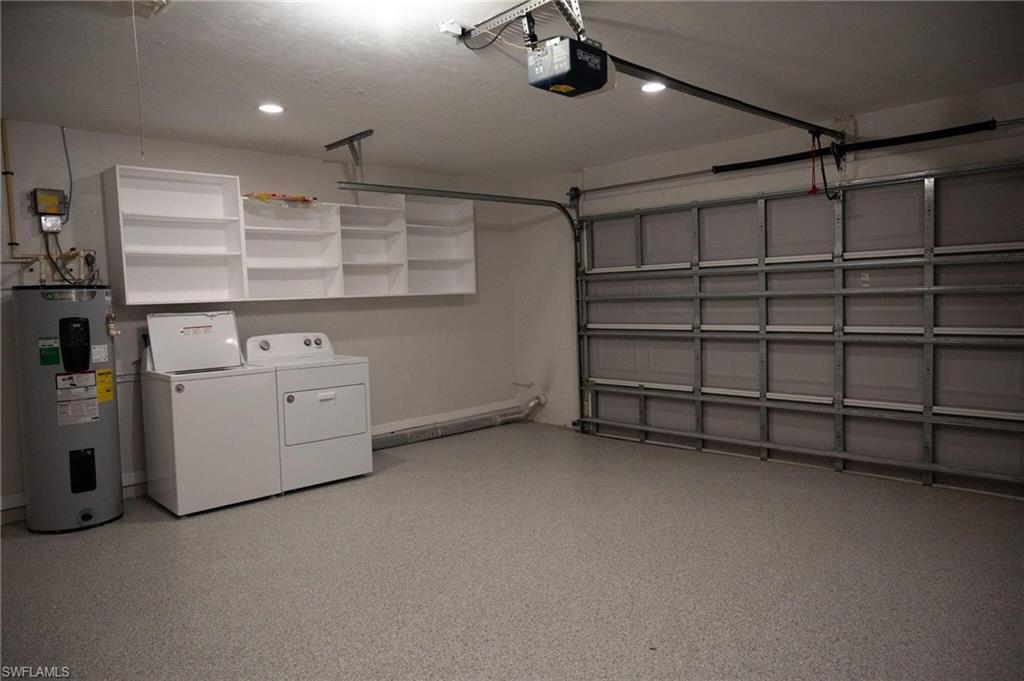 Garage featuring water heater, washer and clothes dryer, a garage door opener, and recessed lighting