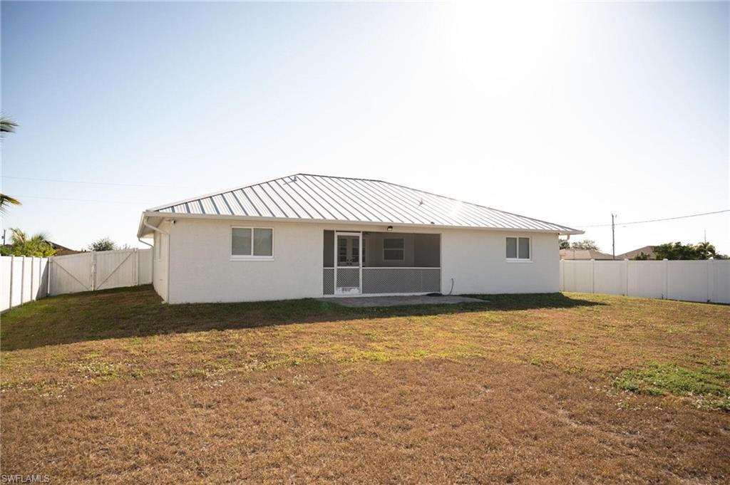 Rear view of property featuring a fenced backyard, a patio, stucco siding, and a metal roof