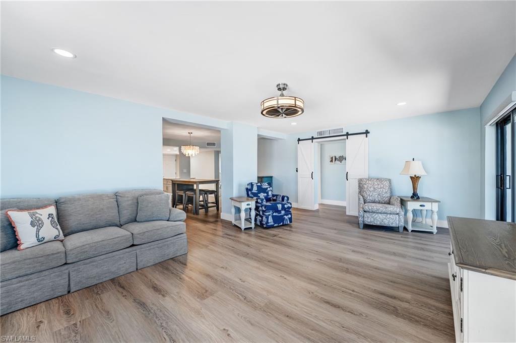 Huge Living area featuring a barn door, a chandelier, light wood-type flooring, and recessed lighting