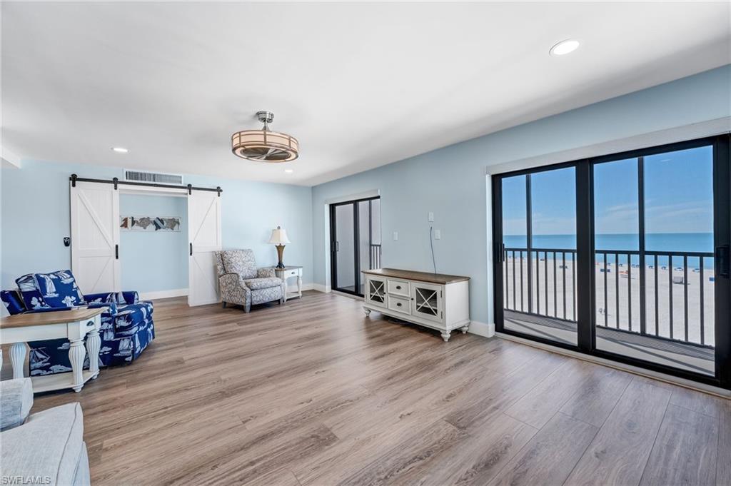 Every seat has a waterfront view!  Living room featuring a barn door, recessed lighting, light wood-style floors, and a water view