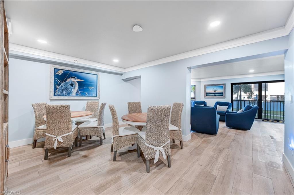 Community space for having a party or playing games featuring light wood finished floors, ornamental molding, and recessed lighting