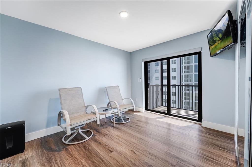 Guest bedroom with a private balcony, wood finished floors and baseboards