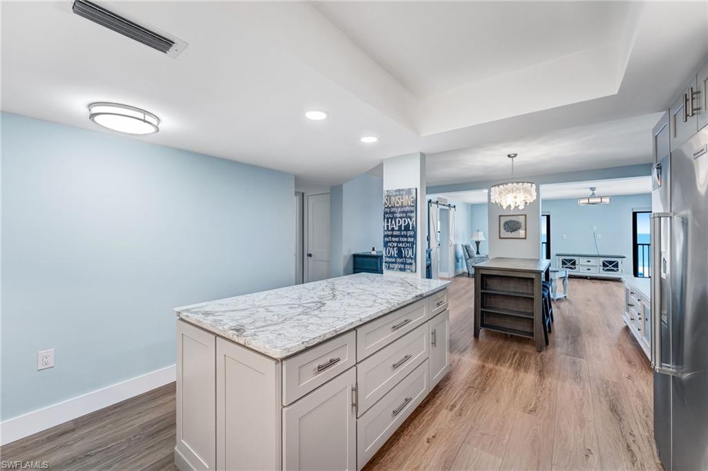 Big kitchen island, light stone counters, and lots of drawers and cabinets