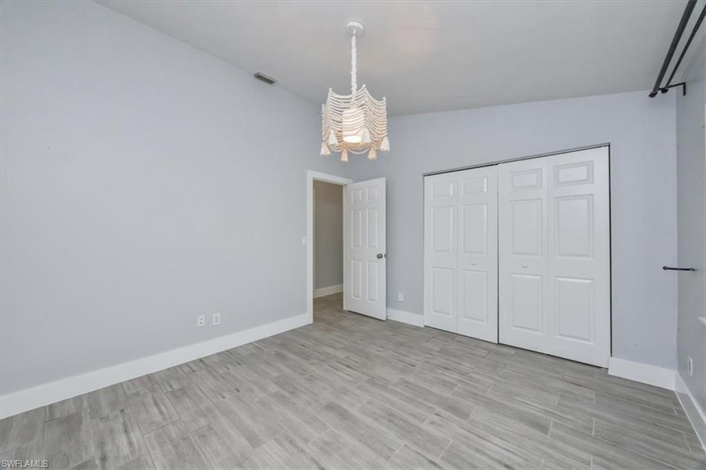 Unfurnished bedroom featuring light wood finished floors, a closet, and lofted ceiling