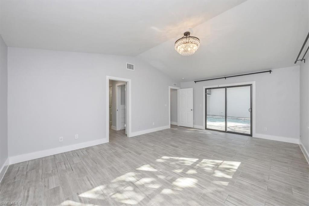 Unfurnished room featuring lofted ceiling, wood finish floors, and a chandelier