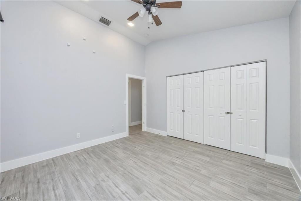 Unfurnished bedroom featuring light wood-style flooring, high vaulted ceiling, ceiling fan, and a closet