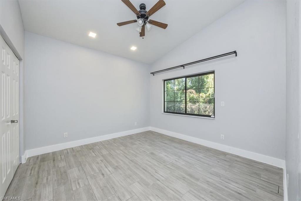 Empty room with vaulted ceiling, light wood-style floors, ceiling fan, and recessed lighting