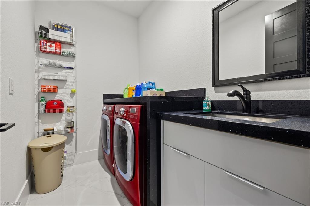 Laundry room with washer and clothes dryer, light marble finish floors, and a textured wall