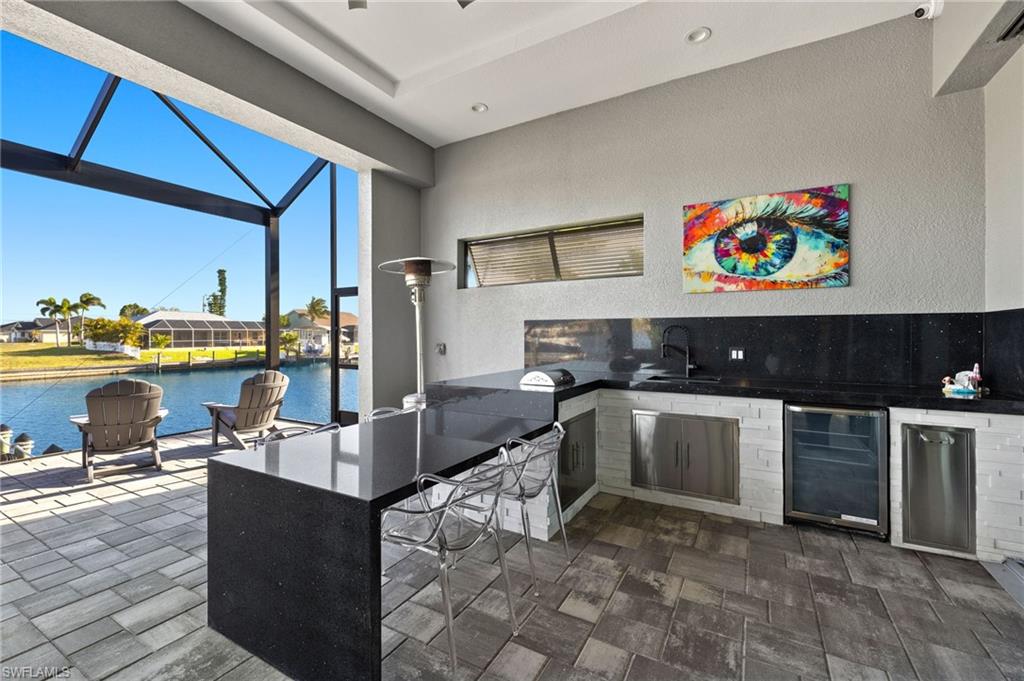 View of patio / terrace featuring area for grilling, a water view, beverage cooler, a lanai, and a sunroom