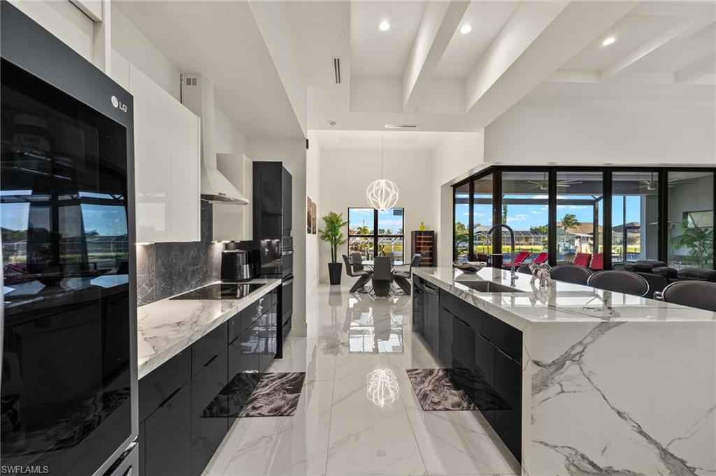 Kitchen with modern cabinets, light stone countertops, pendant lighting, a high ceiling, and beamed ceiling
