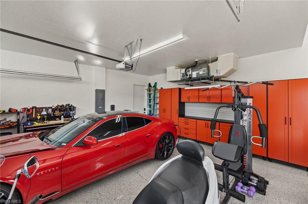 Garage featuring electric panel, heating unit, and a garage door opener