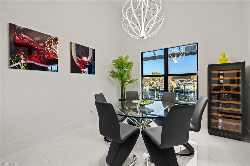 Dining room featuring beverage cooler, marble finish flooring, and a chandelier