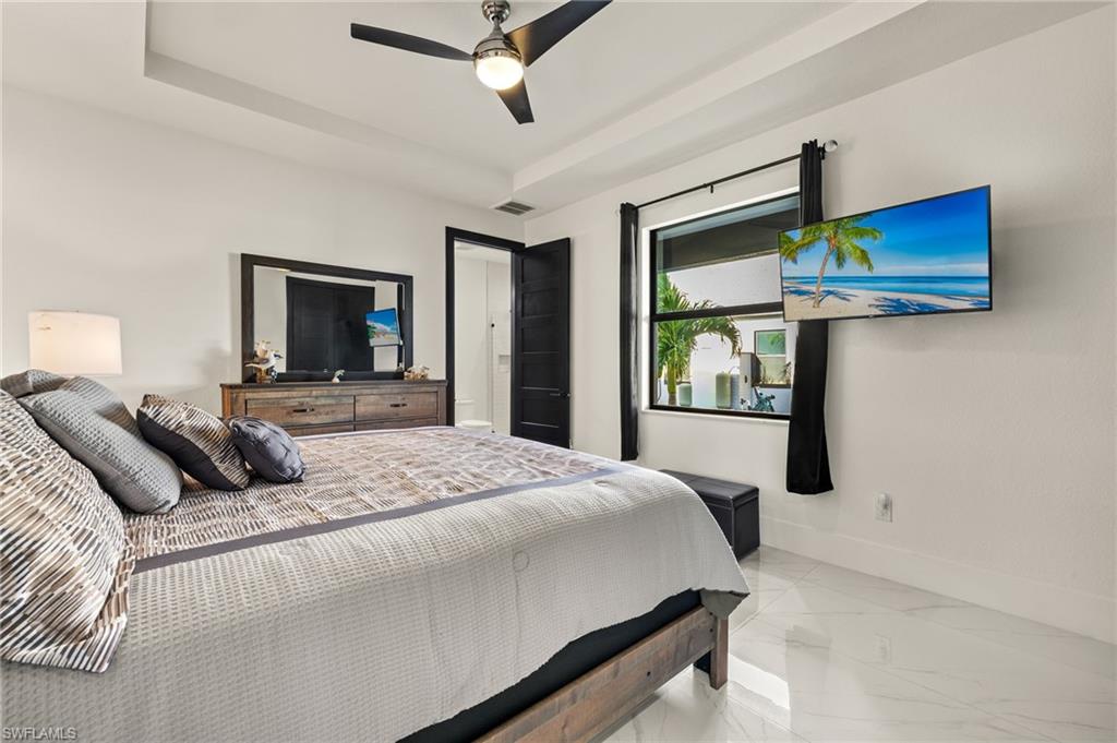 Bedroom with a raised ceiling, a ceiling fan, and marble finish flooring