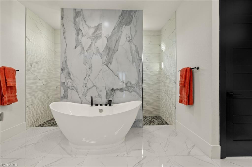 Bathroom with a freestanding tub, a marble finish shower, and marble tiled floors