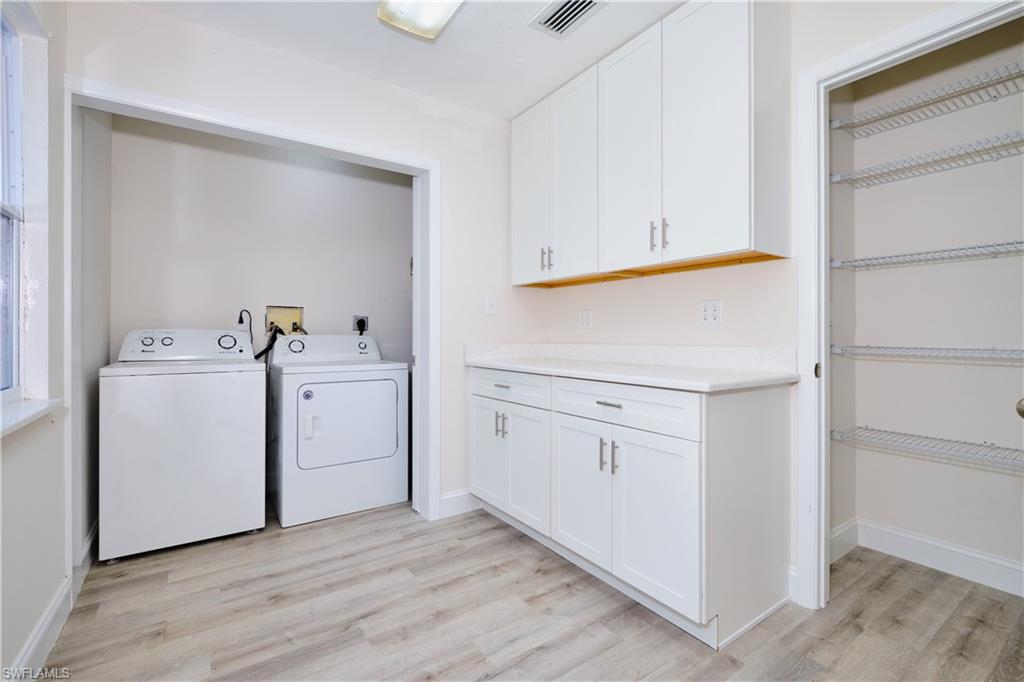 Laundry area featuring washing machine and clothes dryer, light wood-type flooring, and cabinet space