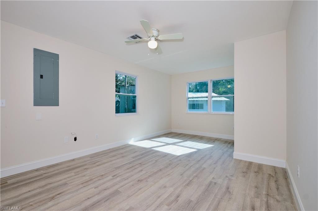 Empty room featuring electric panel, light wood-style floors, healthy amount of natural light, and ceiling fan