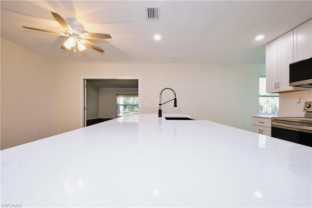 Kitchen with white cabinets, recessed lighting, stainless steel electric range oven, light stone counters, and ceiling fan