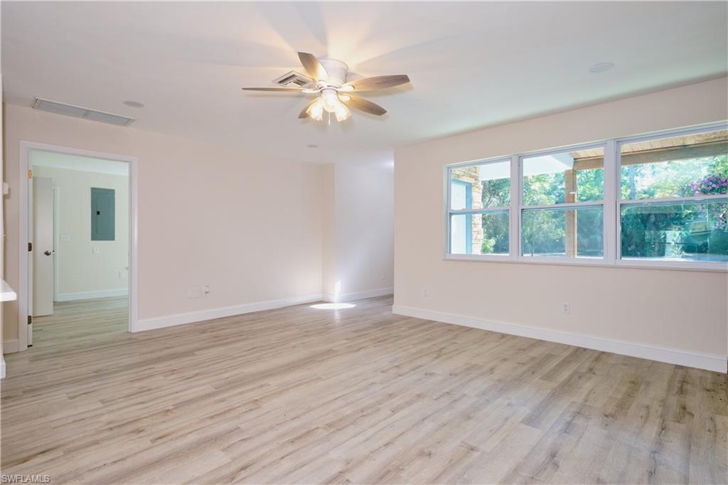 Empty room featuring light wood finished floors, electric panel, and ceiling fan