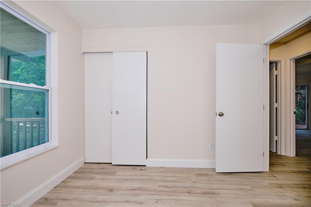 Unfurnished bedroom featuring multiple windows, light wood-style flooring, and a closet