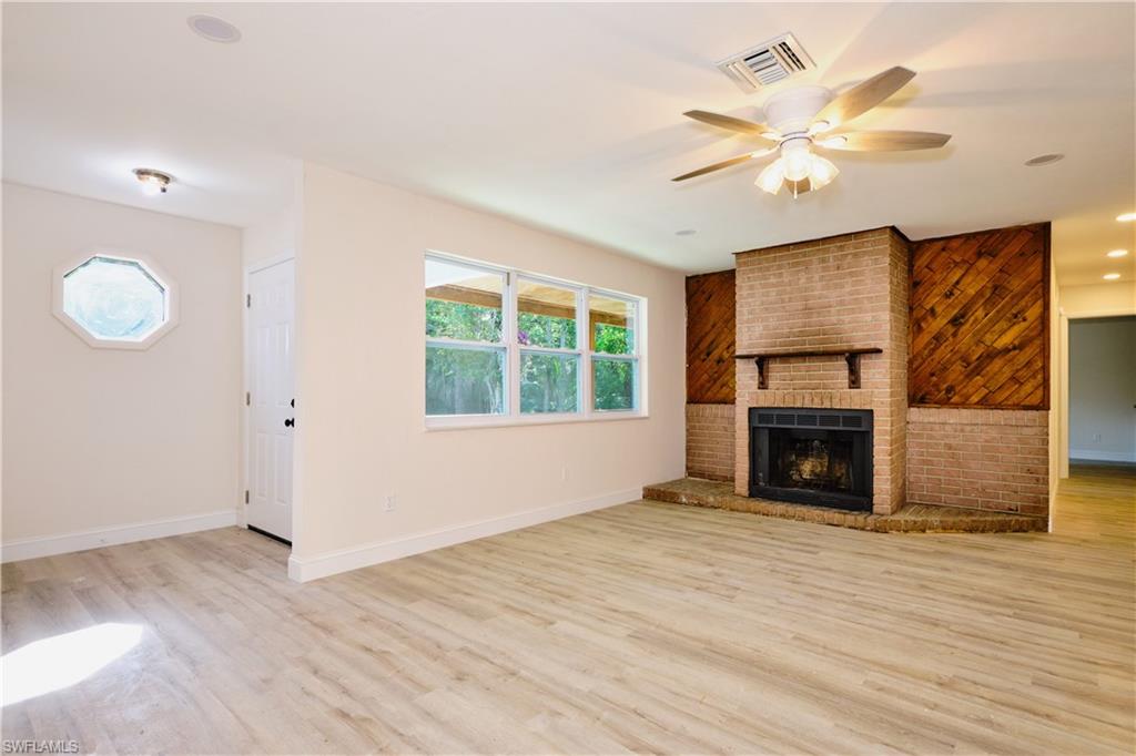 Unfurnished living room featuring light wood-style floors, ceiling fan, a brick fireplace, and recessed lighting