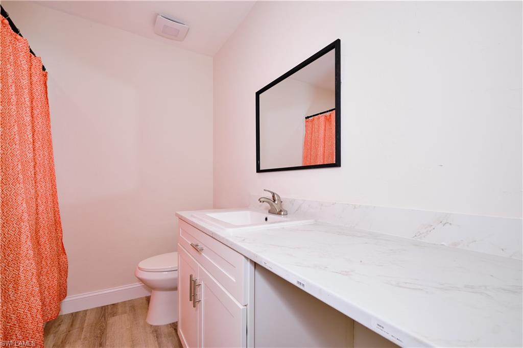 Full bathroom featuring a shower with shower curtain, vanity, and light wood-type flooring