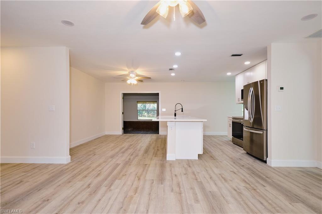 Kitchen featuring white cabinets, stainless steel appliances, an island with sink, recessed lighting, and open floor plan