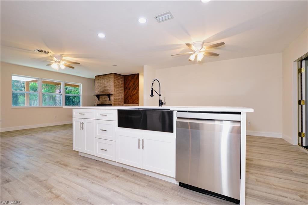 Kitchen featuring a ceiling fan, dishwasher, white cabinetry, recessed lighting, and an island with sink