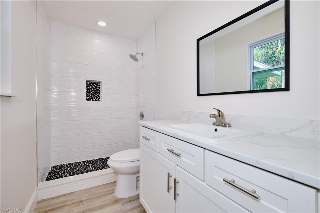 Full bath with a stall shower, vanity, light wood finished floors, and recessed lighting