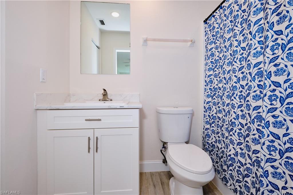 Bathroom with curtained shower, vanity, and light wood-type flooring